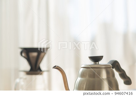 [Japan] A silver kettle and a coffee dripper placed in front of the window curtain where the morning sun shines 94607416