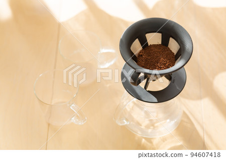 [Japan] Coarsely ground coffee beans in a coffee server, glass and dripper placed on the floor by the window where the morning sun shines 94607418