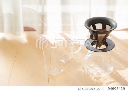 [Japan] Coarsely ground coffee beans in a coffee server, glass and dripper placed on the floor by the window where the morning sun shines 94607419