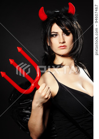 A beautiful, sexy woman in a devil costume, a demon with horns and pitchforks, a trident, in a red dress. American, dress for a costume party Halloween. Choker on the neck. Bright makeup A beautiful, sexy woman in a devil costume, a demon with horns and pitchforks, a trident, in a red dress. American, dress for a costume party Halloween. Choker on the neck. Bright makeup 94607467