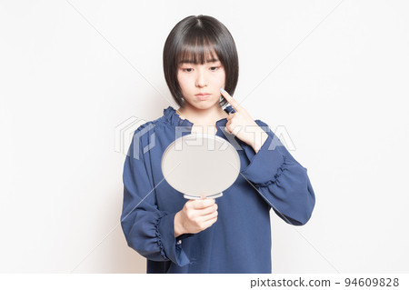 年輕女子在鏡子裡看著她的皮膚 年輕女子在鏡子裡看著她的皮膚 94609828