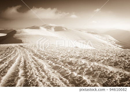 Snow covered fir trees on the background of mountain peaks. Panoramic view of the picturesque snowy winter landscape. Snow covered fir trees on the background of mountain peaks. Panoramic view of the picturesque snowy winter landscape. 94610082