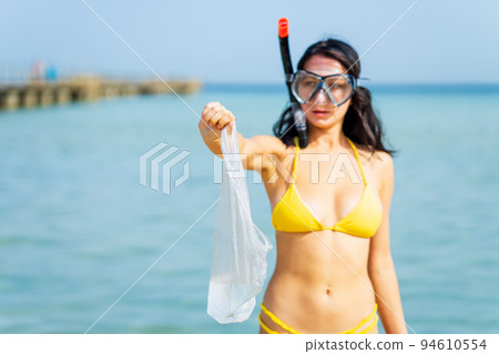 woman in yellow bikini and scuba picking up a plastic trash from sea woman in yellow bikini and scuba picking up a plastic trash from sea 94610554