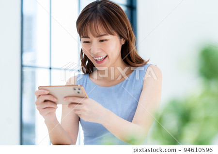 A woman watching a video on a smartphone 94610596