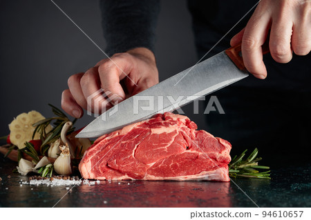 Chef cutting raw beef meat. Chef cutting raw beef meat. 94610657