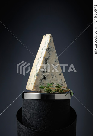 Blue cheese with thyme on a black background. 94610671