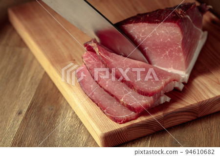 Dry-cured pork fillet on a cutting board. 94610682