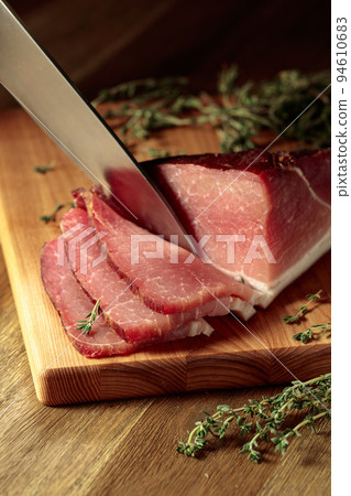 Dry-cured pork with thyme on a wooden cutting board. Dry-cured pork with thyme on a wooden cutting board. 94610683