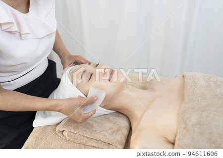 A woman receiving a facial esthetic using Guasha 94611606