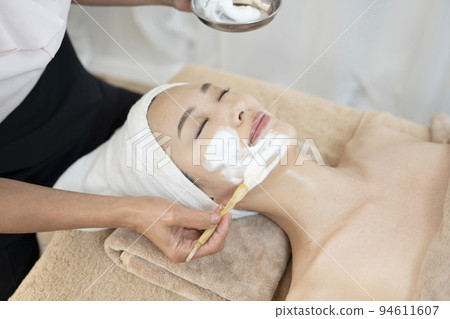 A woman receiving a facial esthetic using foam 94611607