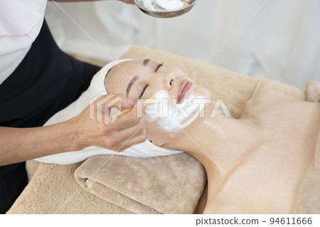 A woman receiving a facial esthetic using foam 94611666
