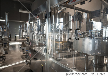 Sicily, Italy. August 26, 2022. Automatic wine filling system by metallic machinery in factory. Procedure of wine manufacturing with modern technology in winery. 94611924