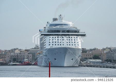 Messina, Sicily, Italy. August 26, 2022. Majestic cruise ship moored at harbor. Luxurious nautical vessel at Mediterranean port in ancient city of Messina with blue sky in background. 94611926