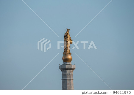 Messina, Sicily, Italy. August 26, 2022. Low angle close-up view of beautiful Statue of Golden Madonna. Famous religious female sculpture monument at Messina port with blue sky in background. 94611970