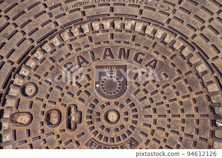 Sunlight shines on a manhole cover on a cobblestone street in Palanga, Lithuania. Sunlight shines on a manhole cover on a cobblestone street in Palanga, Lithuania. 94612126
