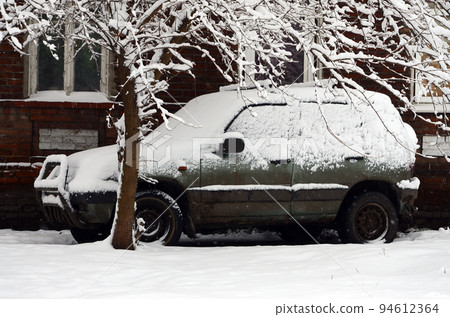 Photo of a car covered in a thick layer of snow. Consequences of heavy snowfall 94612364