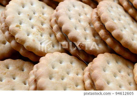 Detailed picture of round sandwich cookies with coconut filling. Background image of a close-up of several treats for tea 94612605