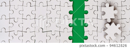 The green path is laid on the platform of a white folded jigsaw puzzle. The missing elements of the puzzle are stacked nearby. Texture image with space for text The green path is laid on the platform of a white folded jigsaw puzzle. The missing elements of the puzzle are stacked nearby. Texture image with space for text 94612826