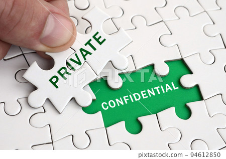 The human hand fills the last missing elements of the surface from the jigsaw puzzle. Image with words private and confidential 94612850