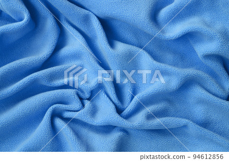 The blanket of furry blue fleece fabric. A background of light blue soft plush fleece material with a lot of relief folds The blanket of furry blue fleece fabric. A background of light blue soft plush fleece material with a lot of relief folds 94612856