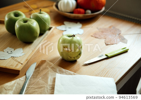 Halloween Fruit ideas. Halloween green apple with creepy carved face on wooden table at home. Healthy Halloween Snacks Halloween Fruit ideas. Halloween green apple with creepy carved face on wooden table at home. Healthy Halloween Snacks 94613569