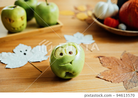Halloween Fruit ideas. Halloween green apple with creepy carved face on wooden table at home. Healthy Halloween Snacks Halloween Fruit ideas. Halloween green apple with creepy carved face on wooden table at home. Healthy Halloween Snacks 94613570