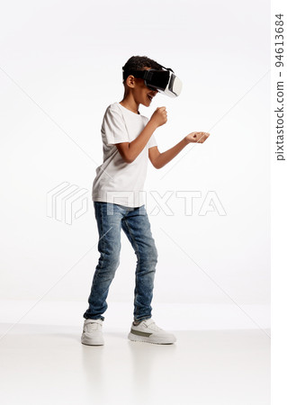 School age boy wearing casual style outfit enjoying 3D technology in virtual reality headset isolated on white background 94613684