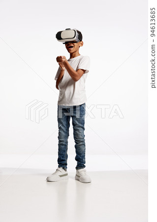 School age boy wearing casual style outfit enjoying 3D technology in virtual reality headset isolated on white background 94613685