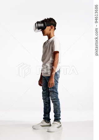 School age boy wearing casual style outfit enjoying 3D technology in virtual reality headset isolated on white background 94613686