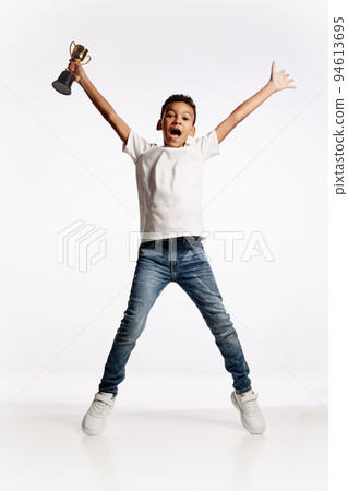 Winner emotions. Happy african little boy jumping with his prize isolated over white background. Kids emotions, winner concept Winner emotions. Happy african little boy jumping with his prize isolated over white background. Kids emotions, winner concept 94613695