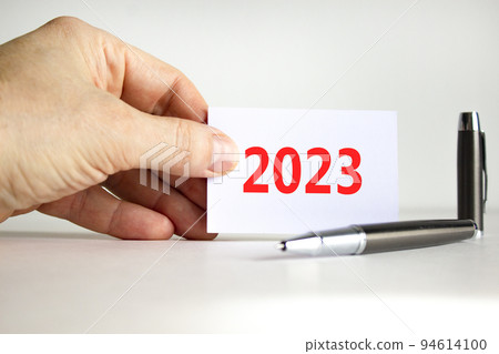 2023 happy new year symbol. White sheet of paper with number 2023. Businessman hand. Metallic pen. Beautiful white table white background. Business and 2023 happy new year concept. 2023 happy new year symbol. White sheet of paper with number 2023. Businessman hand. Metallic pen. Beautiful white table white background. Business and 2023 happy new year concept. 94614100