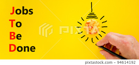 JTBD jobs to be done symbol. Concept words JTBD jobs to be done on yellow paper on a beautiful yellow background. Businessman hand. Light bulb. Business and JTBD jobs to be done concept. Copy space. 94614192