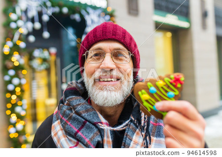 happy man showing green sweet cookie christmas tree shape outdoors in winter market happy man showing green sweet cookie christmas tree shape outdoors in winter market 94614598