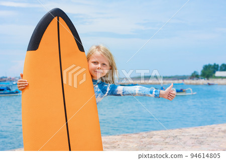 Young surfer with surfboard on tropical sea beach Young surfer with surfboard on tropical sea beach 94614805