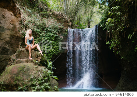 Woman looking at waterfall in tropical rainforest 94614806