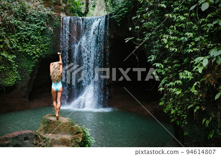 Woman looking at waterfall in tropical rainforest 94614807