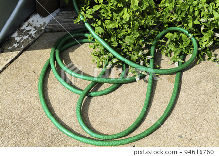 The water hose is on the concrete floor in backyard 94616760