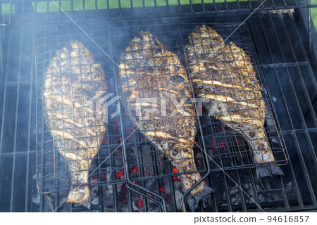Grilling process of dorado fish on a charcoal BBQ grill in the backyard Grilling process of dorado fish on a charcoal BBQ grill in the backyard 94616857