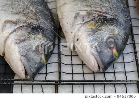 cooking sea fish. Raw dorado fish with spices on bbq mesh. cooking sea fish. Raw dorado fish with spices on bbq mesh. 94617000