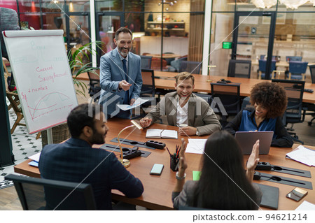 Mature business coach or speaker make flip chart presentation to diverse businesspeople at meeting 94621214