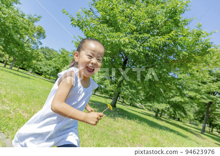 A girl running in an early summer park with dandelions 94623976