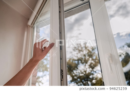 One sided open window. A hand opens a vinyl plastic window on a blue sky background. 94625239