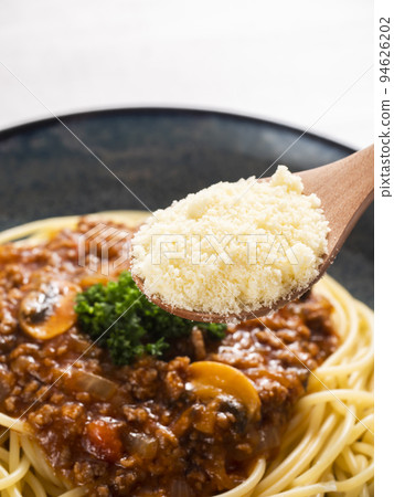 Sprinkle grated cheese on spaghetti meat sauce 94626202