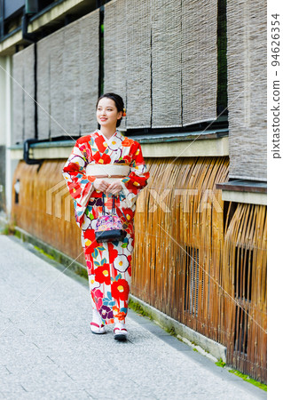 A woman in a kimono walks through the streets of Kyoto where bamboo arrows line the streets A woman in a kimono walks through the streets of Kyoto where bamboo arrows line the streets 94626354