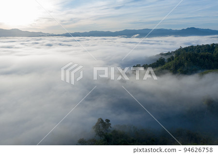 aerial view scenery sunrise above the mountain in tropical rainforest. slow floating fog blowing cover on the mountain look like as a sea of mist. beautiful sunrise in the mist background. aerial view scenery sunrise above the mountain in tropical rainforest. slow floating fog blowing cover on the mountain look like as a sea of mist. beautiful sunrise in the mist background. 94626758