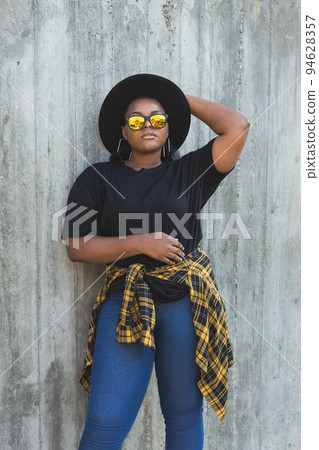 Close-up portrait stylish young African American girl with curly hair in fashionable sunglasses in urban with copy space and place for advertising - summer hipster photos with instagram style Close-up portrait stylish young African American girl with curly hair in fashionable sunglasses in urban with copy space and place for advertising - summer hipster photos with instagram style 94628357