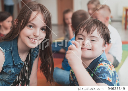 A girl and a boy with Down's syndrome in each other's arms spend time together in a preschool institution 94628849