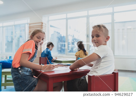 Cute girl and boy sit and draw together in preschool institution Cute girl and boy sit and draw together in preschool institution 94629027