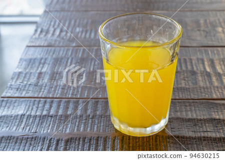 Orange juice drink, a close up of glass of tasty tropical juice beverage on wood table. Orange juice drink, a close up of glass of tasty tropical juice beverage on wood table. 94630215