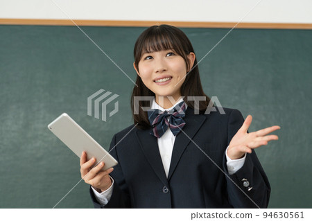 A high school girl giving a presentation with a tablet in her hand in a school classroom 94630561